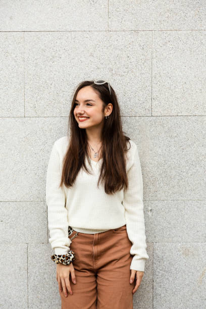 istock Smiling girl leaning against a wall 1357282537