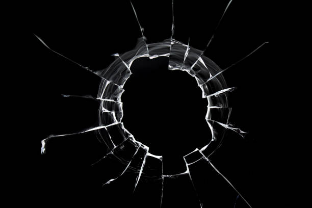 istock A hole from a shot in the window. Cracked texture isolated on black background. 1357284395