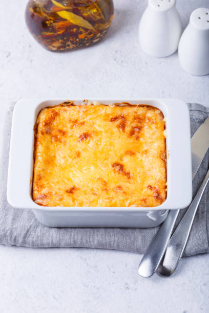 istock Moussaka with meat, eggplant, tomatoes, potatoes, bechamel sauce and cheese on a white plate. Traditional Greek dish. Close-up. 1357287363