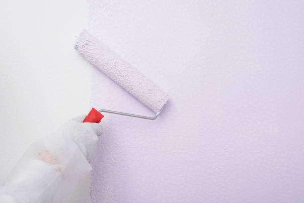 istock hand in a glove paints over a white wall, close-up 1357291423