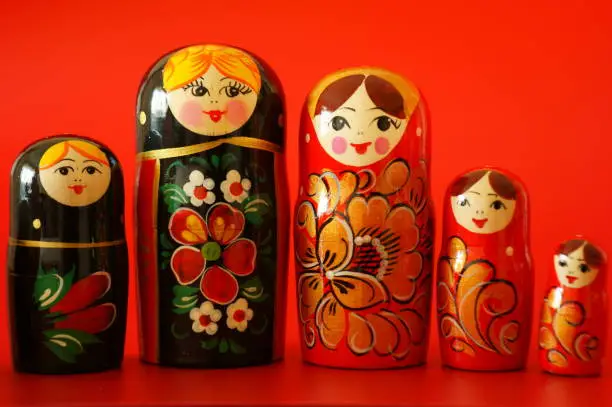 A group of wooden nesting dolls in close-up on a red background.
