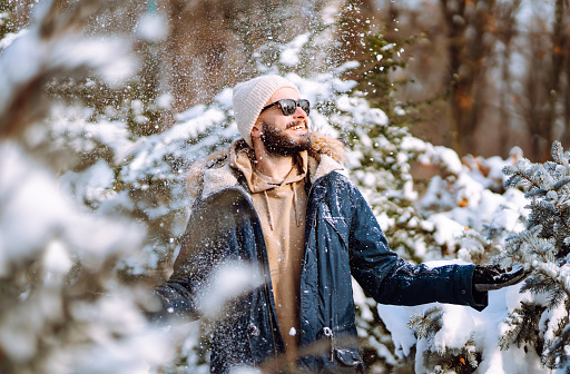 Portrait of  young man  in snowy winter forest. Season, christmas, travel and people concept.