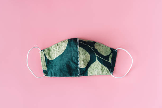 istock Green protective mask with print on blue background 1357297847