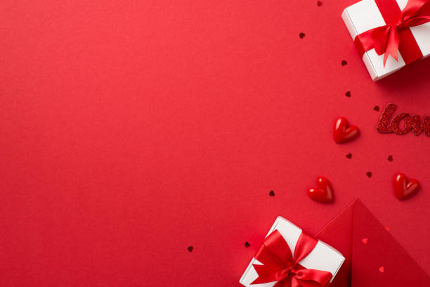 istock Top view photo of valentine's day decorations white gift boxes with red bows envelope small hearts inscription love and confetti on isolated red background with empty space 1357300174
