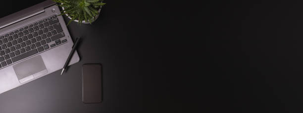 istock Copy space office black table with laptop, notebook, pencil and coffee cup with plat. 1357302824