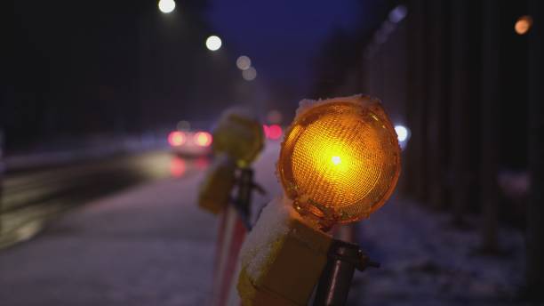 istock Maintenance Roadworks Barrier Orange Caution Lamps Blinking in Sequence by Busy Icy Road with High Congestion Traffic on Winter Evening 1357302905