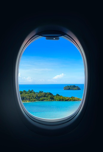 looking through the window of an airplane to the island.Summer travel destination concept.