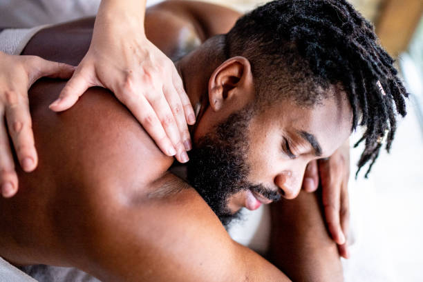 homme mi-adulte recevant un massage sur les épaules dans un spa - massaging men beauty spa beauty treatment photos et images de collection