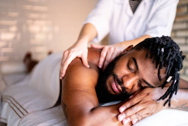 Mid adult man receiving massage on shoulders at a spa Mid adult man receiving massage on shoulders at a spa black male massage stock pictures, royalty-free photos & images