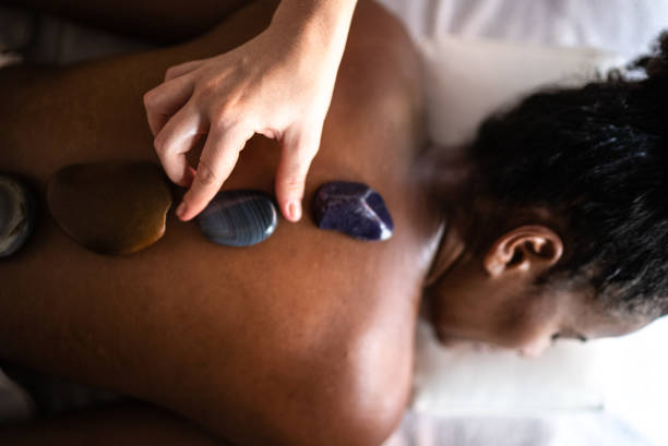 istock Therapist putting hot stones on woman's back at a spa 1357312483