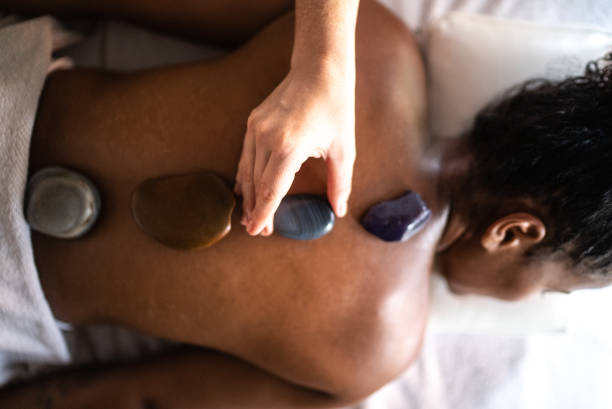 istock Therapist putting hot stones on woman's back at a spa 1357312484