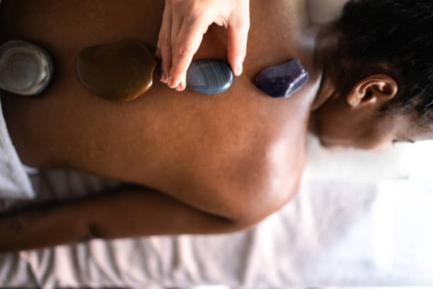terapeuta che mette pietre calde sulla schiena della donna in una spa - spa treatment health spa wellbeing lastone therapy foto e immagini stock