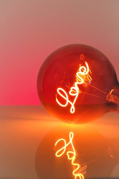 istock Valentine's Day. Love light bulb.Turning on a light bulb.red Light bulb with the inscription love on a red and yellow background. 1357315618