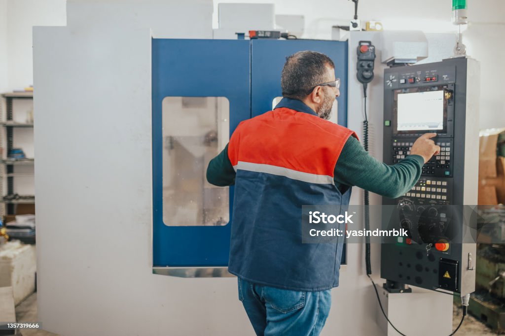 senior man working on cnc machine CNC Machine Stock Photo