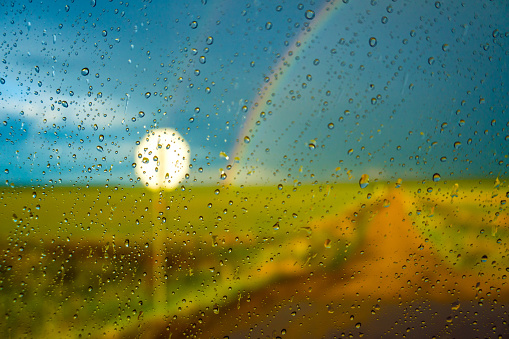 blurred rainbow view through car window with raindrops