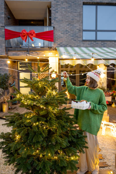 istock Woman decorating Christmas tree at backyard 1357325043