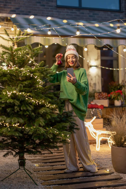 istock Woman decorating Christmas tree at backyard 1357325223
