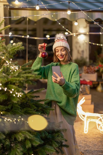 istock Woman decorating Christmas tree at backyard 1357325232