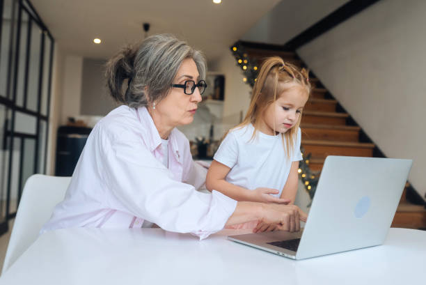 istock Child and granny looking at the camera with laptop 1357326845
