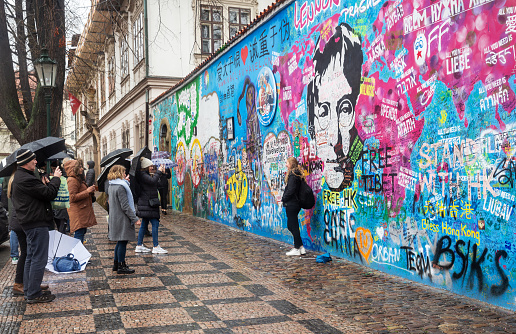 Prague, March 11, 2020: People take a photo at the John Lennon wall in Prague