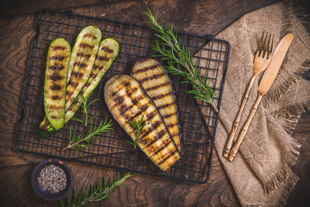 zucchine grigliate e fette di melanzane su una griglia di raffreddamento su sfondo di legno, vista dall'alto - grilled vegetable eggplant zucchini foto e immagini stock