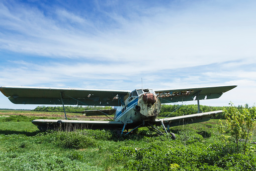 An old Soviet plane stands on the ground in a field