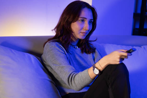 istock beautiful woman changing channels with remote 1357334459