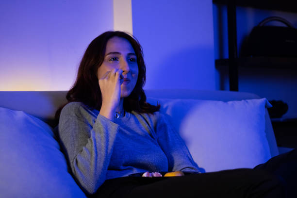 istock redhead young woman eating fruit while watching tv 1357334659