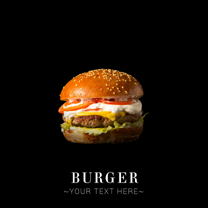 Savory burger with beef meat cutlet, melted cheese, lettuce, tomato slices, creamy sauce isolated on black background. Text space web banner