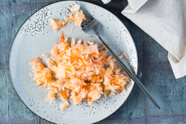 istock Fresh sauerkraut with carrots and a fork on a plate on the table. Fermentation and a vegetarian diet. Top view. Close-up 1357338548