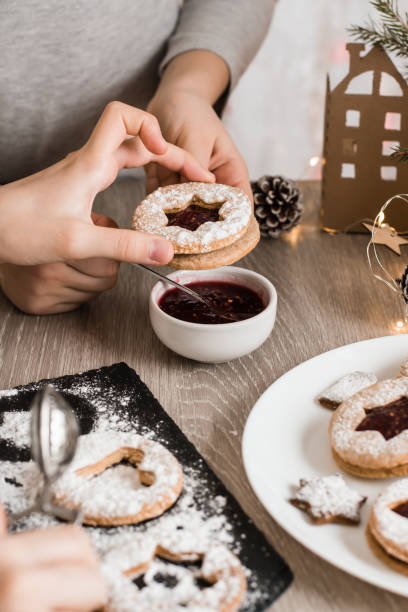 istock Children's hands fold Linzer cookies with berry jam on the kitchen table. Cooking Christmas treats. Lifestyle 1357339380