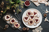 Ready Linzer cookies with berry jam on a plate and Christmas decorations on a dark background. Cooking Christmas treats. Lifestyle. Top view