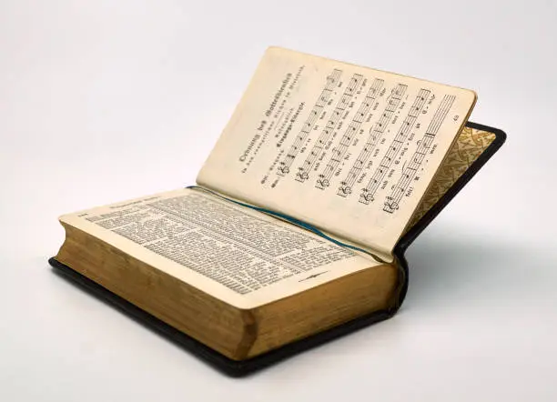 An old used German prayer and song book with gilded pages from 1914. The edges are finished with real gold. Isolated on a white background. The used script is Fraktur.