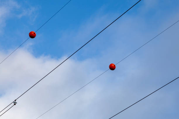 Electric wires with red plastic balls attached to them.