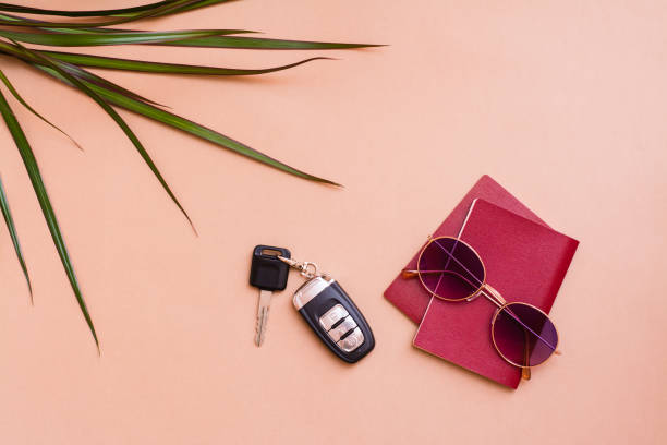Bright travel flat lay with sunglasses, passports, palm leaves and car keys on a beige background. Car travel. Top view Bright travel flat lay with sunglasses, passports, palm leaves and car keys on a beige background. Car travel. Top view car keys table stock pictures, royalty-free photos & images