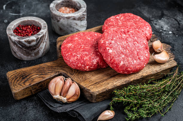 котлеты для гамбургеров из сырой телятиной с травами и специями. черный фон. вид сверху - cutlet meat steak veal стоковые фото и изображения