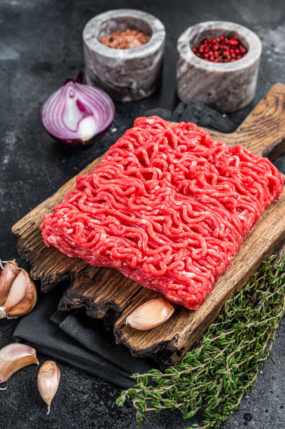 istock Raw Mince, minced Ground beef meat on a cutting board. Black background. Top view 1357342605