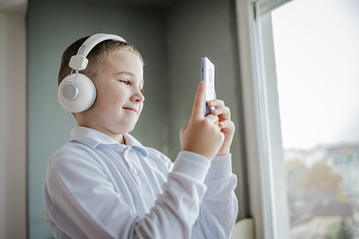 A cute little boy is playing video games on a mobile phone