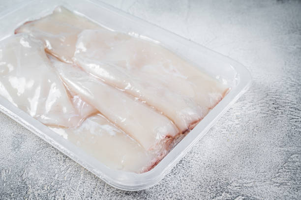 istock Fresh Raw Squid or Calamari in a vacuum package on a kitchen table. White background. Top view 1357345168