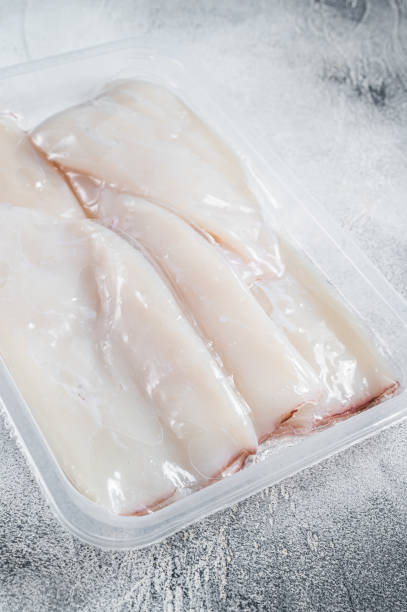 istock Fresh Raw Squid or Calamari in a vacuum package on a kitchen table. White background. Top view 1357345174