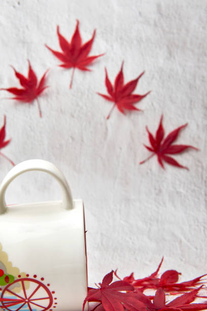 istock Red maple leaves in a mug with flying leaves on background. 1357347120