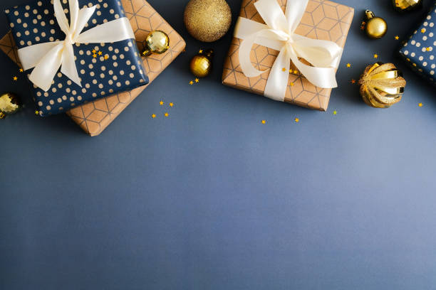 istock Christmas frame top border made of gift boxes and golden balls on dark blue background. Flat lay, top view, copy space. Merry Christmas and Happy New Year banner design. 1357347323