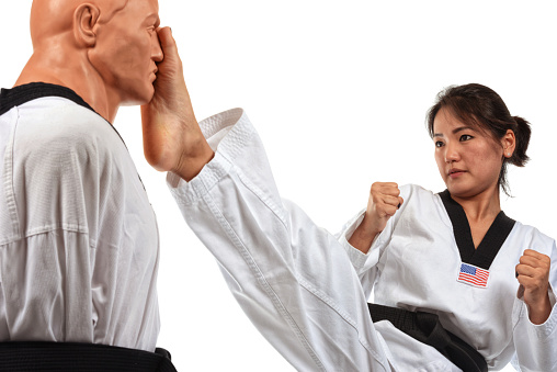 Martial artist kicking a training mannequin in the head.