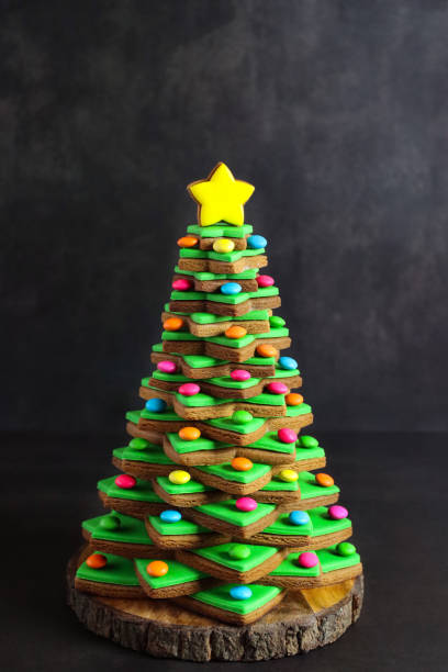 緑のフォンダンアイシングと積み重ねられたジンジャーブレッドスタークッキーから形成されたクローズアップ画像クリスマスツリーは、黄色のアイススタービスケットをトッピングしたマ� - star shape christmas ornament heap stack ストックフォトと画像