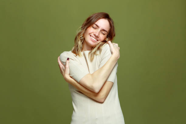 happy relaxed young woman embrace herself smiling on green background. self love, self-care, body positive - women smiling body cheerful imagens e fotografias de stock