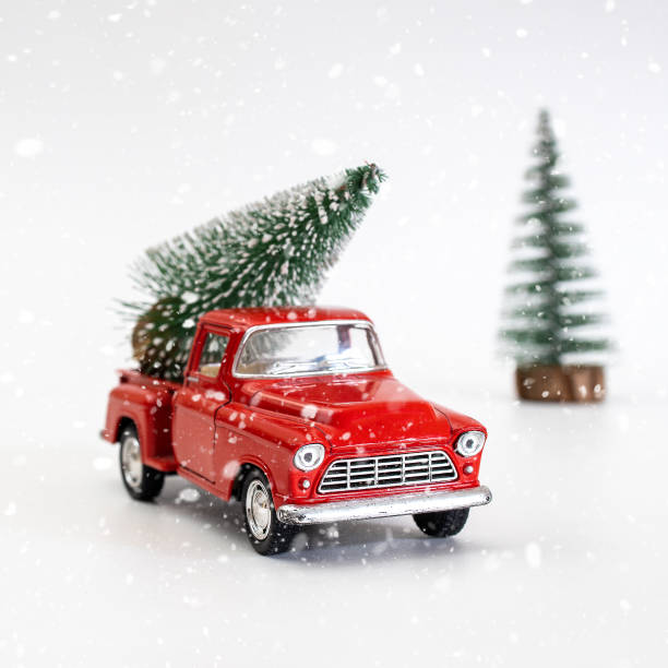 istock miniature red car in the back carries a Christmas tree on a white isolated background under snow, top view. Save the space. Concept, festive Christmas mood, gift delivery. The trend 1357356952