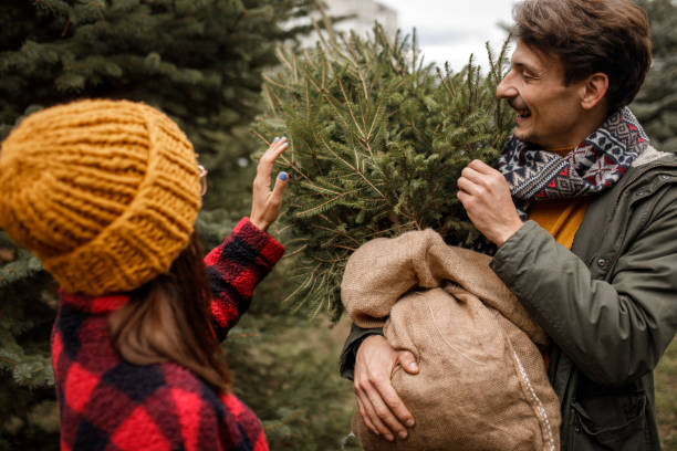 istock Young couple carrying home their Christmas tree 1357357816