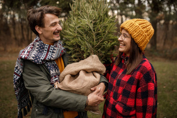 istock Young couple carrying home their Christmas tree 1357357817