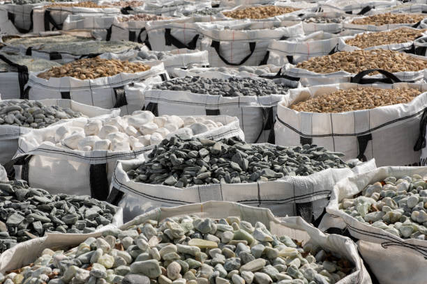 una gran cantidad de bolsas de un metro cúbico llenas de variaciones de piedras trituradas decorativas de jardín en la ferretería. - piedra roca fotografías e imágenes de stock