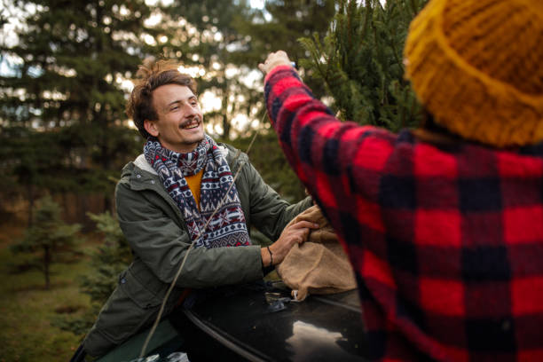 istock Young couple tying Christmas tree to a car roof 1357360458